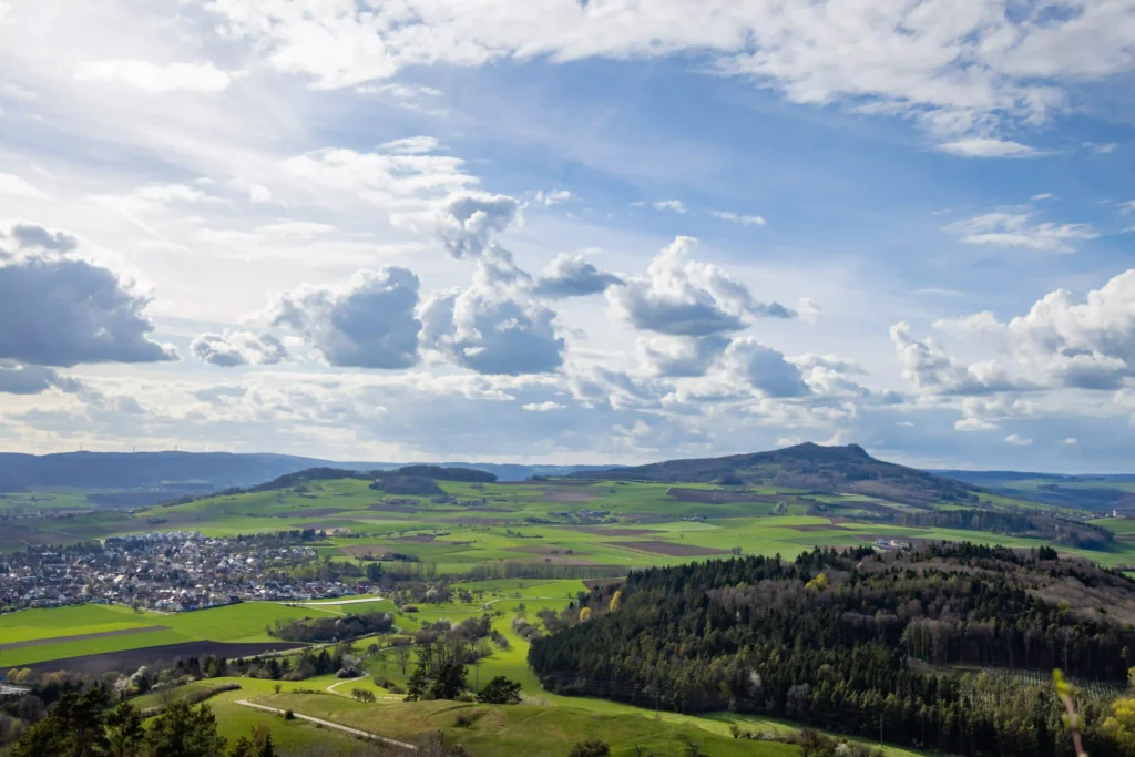 A breathtaking view of green fields and hills stretching under a sky filled with fluffy clouds.