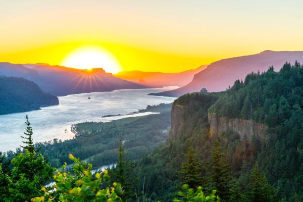 A vibrant sunset over the Columbia River Gorge with glowing skies and serene river views.