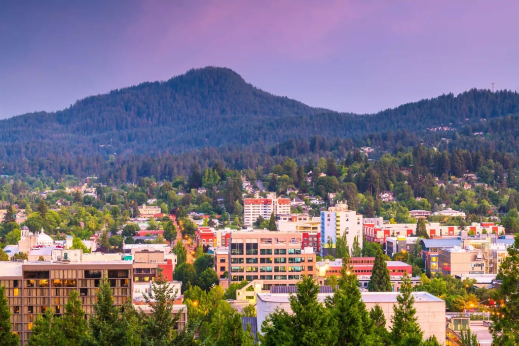 A scenic city view surrounded by greenery and mountains at sunset, perfect for exploring with car service in Portland, Oregon.