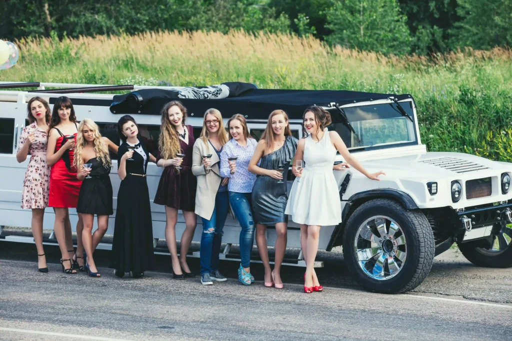 A group of friends poses together in front of a long white stretch limousine, ready for a celebration.